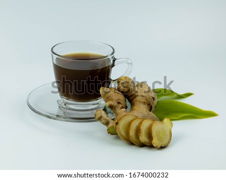 Glass cup of hot ginger tea with ginger rhizome isolated on white background.