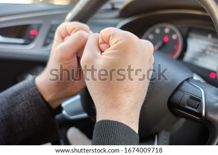 A man in a modern car. Hands hitting the steering wheel with anger. Close up.
