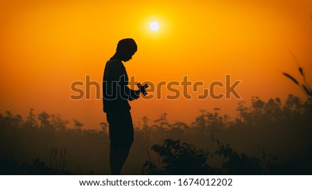 human holding the cross on the head and praying God at morning. christian silhouette concept.