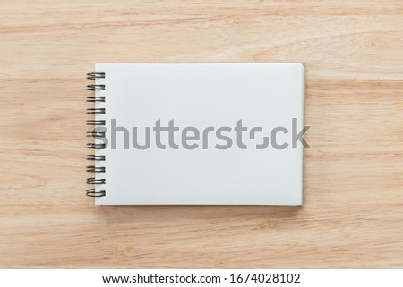 Top view of blank notebook and natural light on wooden table.