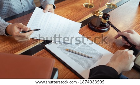 Lawyer working with client discussing contract papers with brass scale about legal legislation in courtroom, consulting to help their customer Royalty-Free Stock Photo #1674033505