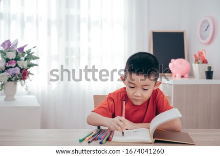 Asian Boy Drawing cartoon on sketchbook in his room.Art Education learning school concept