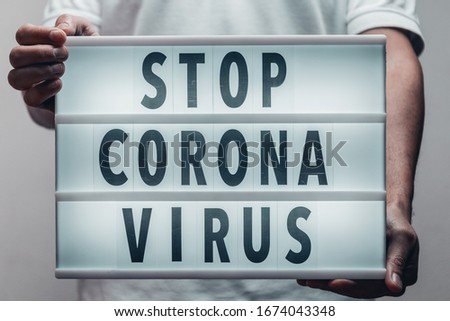 Adult male holding a lightbox text with a message "Stop Corona Virus" written.