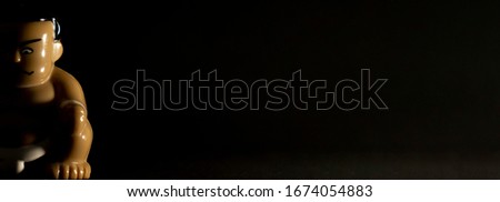 Minimalist black background with sumo wrestler figurine in dramatic lighting