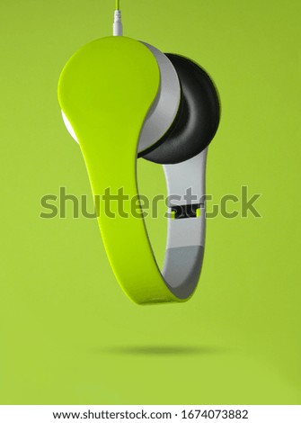 Modern wired stereo headphones hanging down on a green background. Creative art. Minimalism