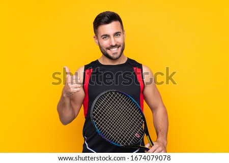 Tennis player man over isolated yellow wall with thumbs up because something good has happened