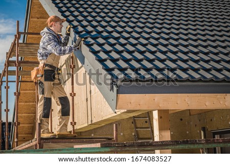 Professional Roofer Worker Finishing Ceramic Roof Tiles Installation. Smiling and Happy Worker on a Scaffolding. Royalty-Free Stock Photo #1674083527
