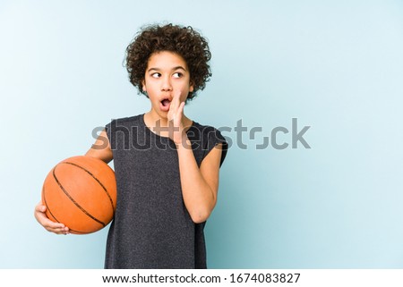 Kid boy playing basketball isolated on blue background is saying a secret hot braking news and looking aside
