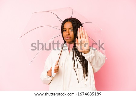 Young african american woman holding an umbrella isolated standing with outstretched hand showing stop sign, preventing you.