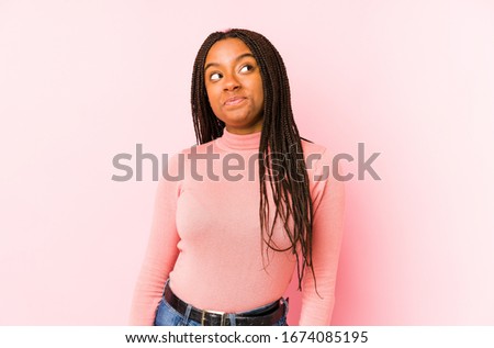 Young african american woman isolated on a pink background dreaming of achieving goals and purposes