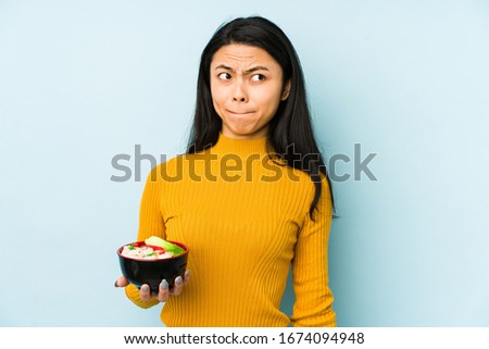Young chinese woman holding noodles isolated excited keeping ok gesture on eye.