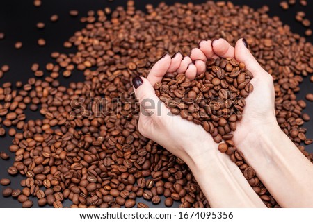 coffee beans in hands over a hill of coffee