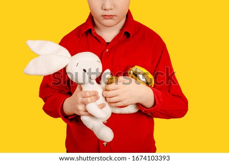 Little boy in bunny ears headband holding Golden Easter eggs