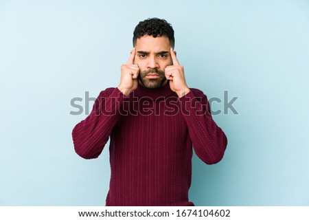 Young mixed race arabic man isolated focused on a task, keeping forefingers pointing head.