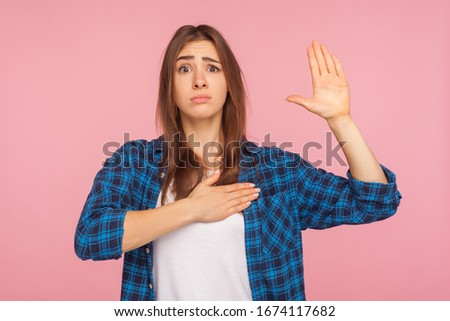 I swear, it's true! Portrait of girl in checkered shirt trying to look honest with funny grimace, keeping hand on chest and giving promise to tell truth. indoor studio shot isolated on pink background