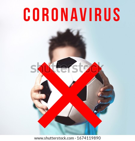 Concept on the issue of cancellation of football matches and competitions due to coronavirus. The guy holds the ball, crossed out with a red brush.