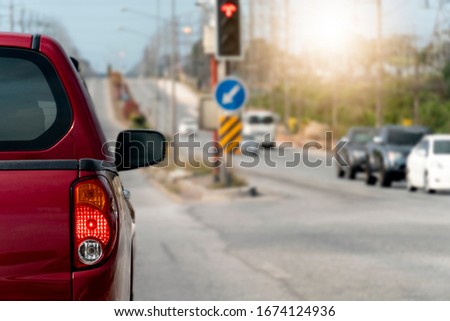 Luxury of pickup red car stop on the junction by traffic light control in across. Traveling in the provinces during the bright period. Open light brake. with many cars.