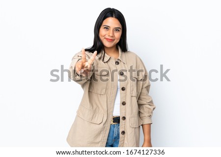 Young latin woman woman isolated on white background smiling and showing victory sign