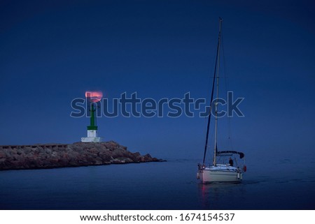 sailing ship entering the mouth of the port with a full moon aligned with the tip of the green lighthouse