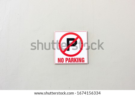 A no parking sign on a white wall.