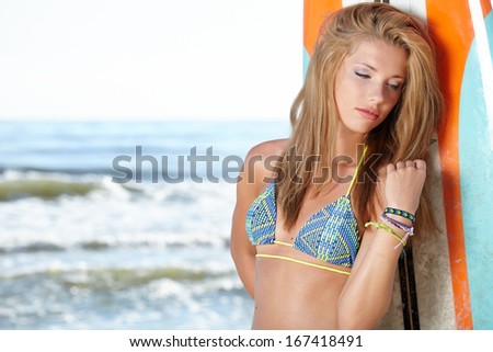 Beautiful Young Woman Surfer Girl in Bikini with Surfboard at a Beach 