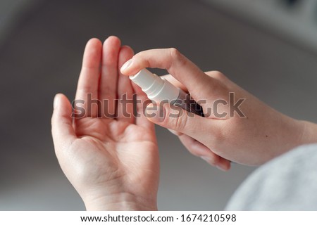 High angle view on unknown female person caucasian woman or girl applying spray disinfection alcohol product on hand disinfecting hands against virus bacteria health prevention in day at home or work Royalty-Free Stock Photo #1674210598