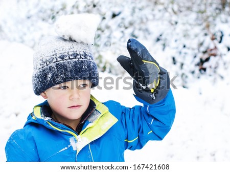 Cute young boy balancing a snowball on his head