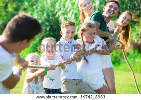 Happy  children with parents playing active games in summer park, tugging war Royalty-Free Stock Photo #1674218983