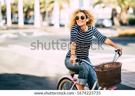Beautiful and cheerful adult young woman enjoy bike ride in sunny urban outdoor leisure activity in the city - happy people portrait - trendy female outside having fun