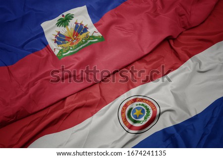 waving colorful flag of paraguay and national flag of haiti. macro