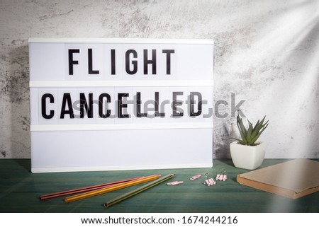 Flight Cancelled. Travel plans, disaster, crisis, quarantine and COVID-19 concept.  White lightbox on a wooden table