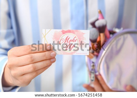 Woman with business card of makeup artist, closeup