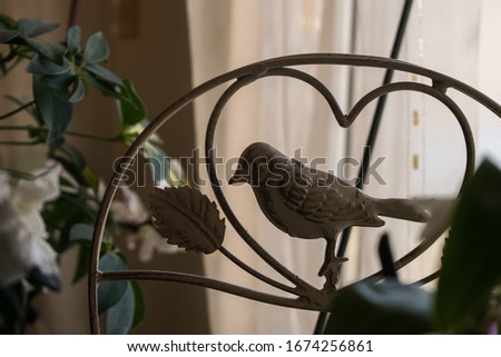 Bird sculpture with flowers inside the house, home decor items.