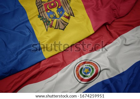 waving colorful flag of paraguay and national flag of moldova. macro