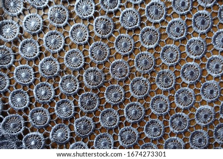 Top view of silver gray crochet lacy fabric on wood