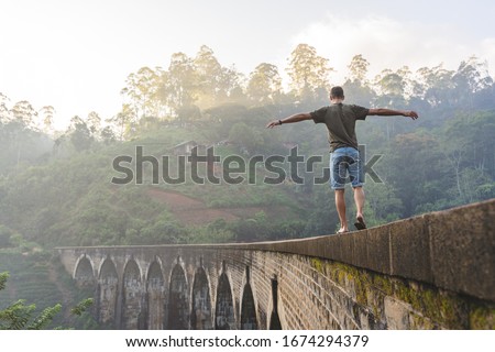 reckless man walking on the edge of the nine-arches bridge in Sri Lanka Royalty-Free Stock Photo #1674294379