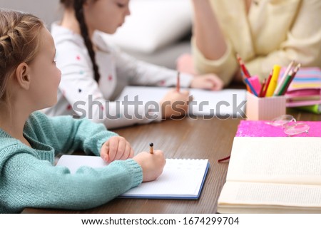 Little girls doing homework with mother at table