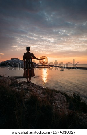 young woman in a hat by the sea at dawn, Peniscola, Spain