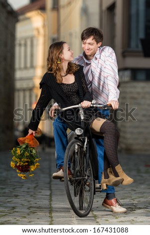 young man and woman riding one bicycle