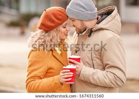 Happy young couple drinking hot cocoa outdoors