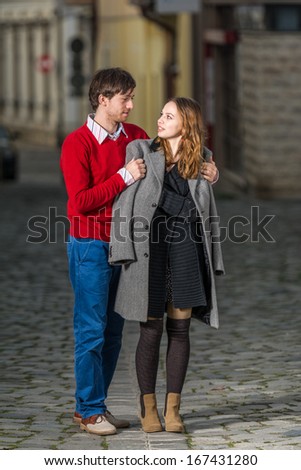 young man putting a coat on his girlfriend's shoulders