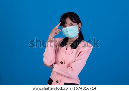 Asian woman masked a protective mask and showing trumb up sign.