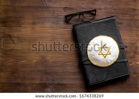 Jewish Kippah Yarmulkes hats with Star of David on Prayer book. Religion Judaisim symbols on wooden table. Top view, space for text
