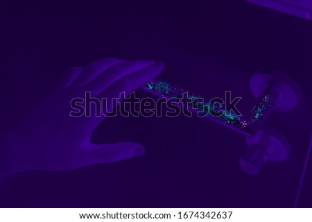 Bacteria, germs and infectious disease revealed with UV light inspection on domestic home door handle - Corona virus spreading on dirty surfaces - Deep cleaning, hand washing and Covid-19 concept Royalty-Free Stock Photo #1674342637
