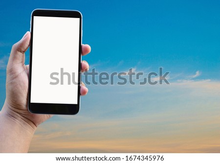 Mobile phone in hand on sky background