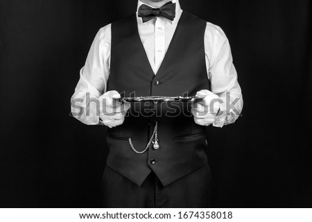 Studio Image of Formal Waiter or Butler Holding Silver Tray with Both Hands. Concept of Service Industry and Professional Hospitality
