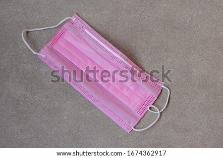 Medical disposable mask pink on a gray background. Copy space.