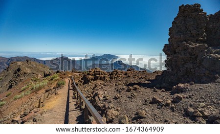 Aerial view of the National Park Caldera de Taburiente, volcanic crater seen from mountain peak of Roque de los Muchachos Viewpoint. El Hierro on horizon line above the clouds. La Palma, Spain