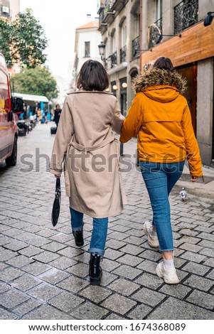 Stock photo of two young girls walking down the street. They are holding hands.