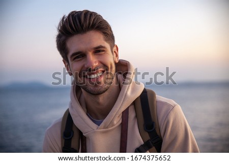 Young good-looking chap is smiling with a gorgeous sunset view  Royalty-Free Stock Photo #1674375652